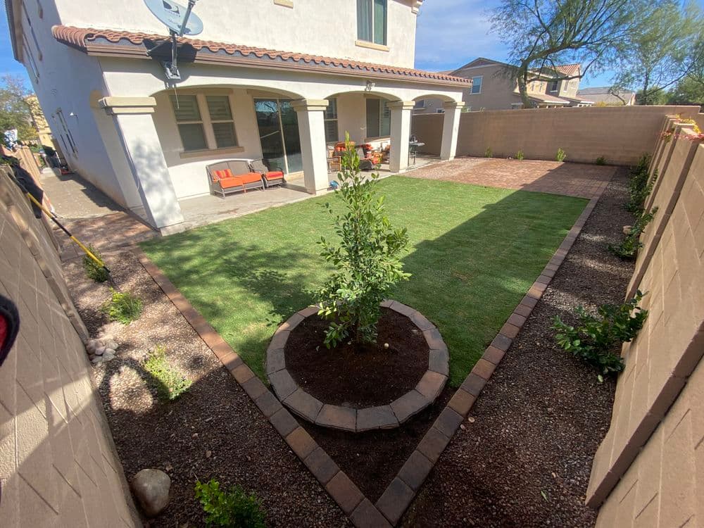 Modern backyard design featuring a landscaped area with grass, trees, and stone pathways.